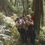 A group of five climbers moving a single large rock to make steps.